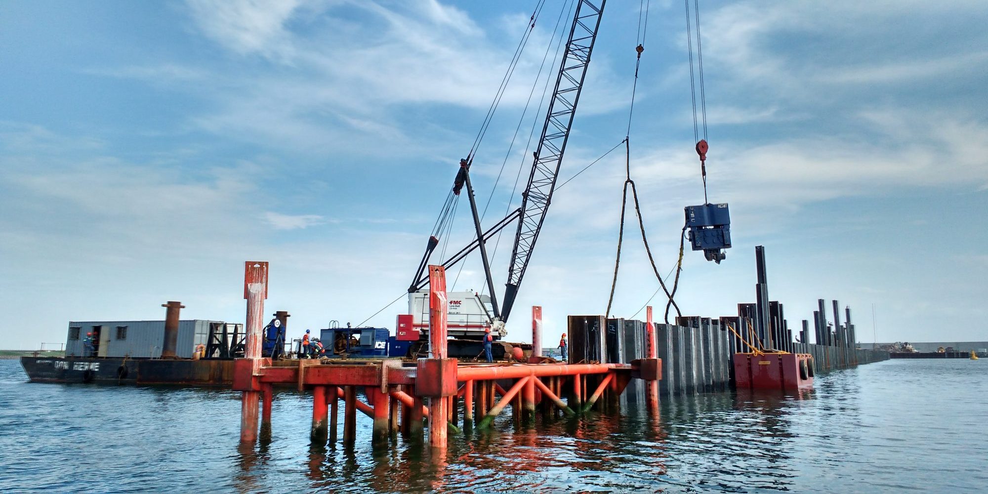 Grúa levantando un vibrohincador , instalando tablestaca de acero en el mar